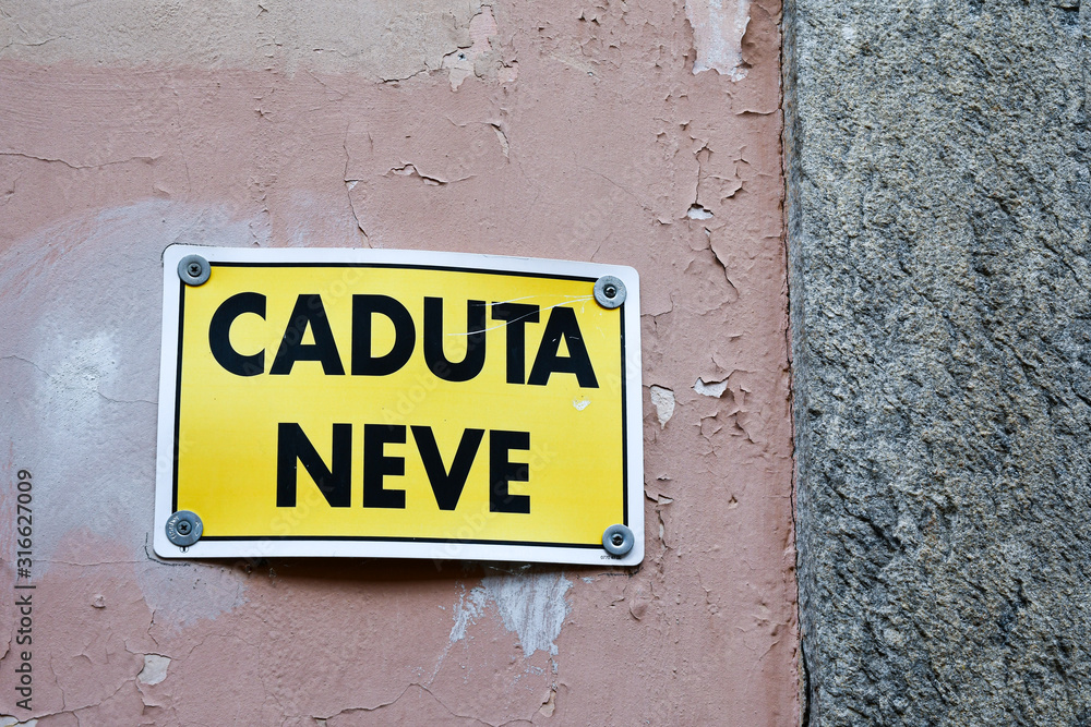 Close-up of an old wall with a warning sign that says: 