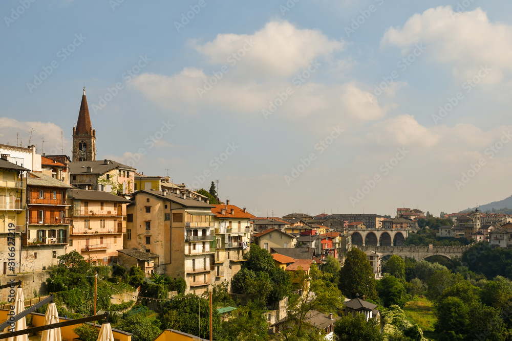Panoramic view of Dronero, a small town in the Alpine Maira Valley, with the bell tower and the medieval Devil's Bridge (Italian: Ponte del Diavolo) built in 1428, Cuneo, Piedmont, Italy