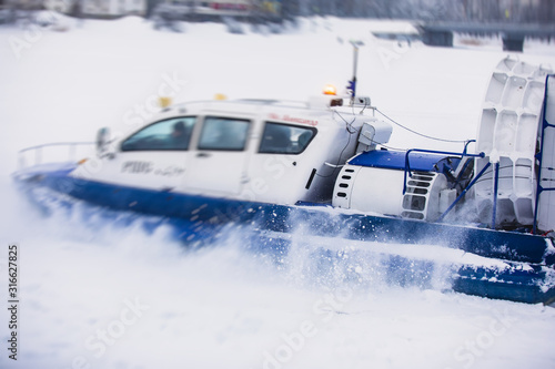 View of rescue team Hovercraft. hover craft transport boat crossing frozen river lake on the ice in the winter snowy day © tsuguliev