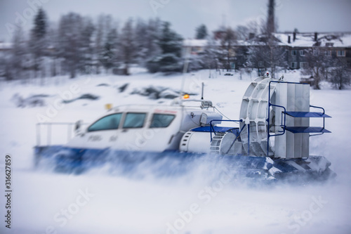 View of rescue team Hovercraft. hover craft transport boat crossing frozen river lake on the ice in the winter snowy day © tsuguliev