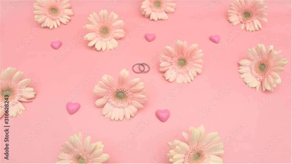 wedding concept. gerbera flowers, hearts, rings on a pink background.