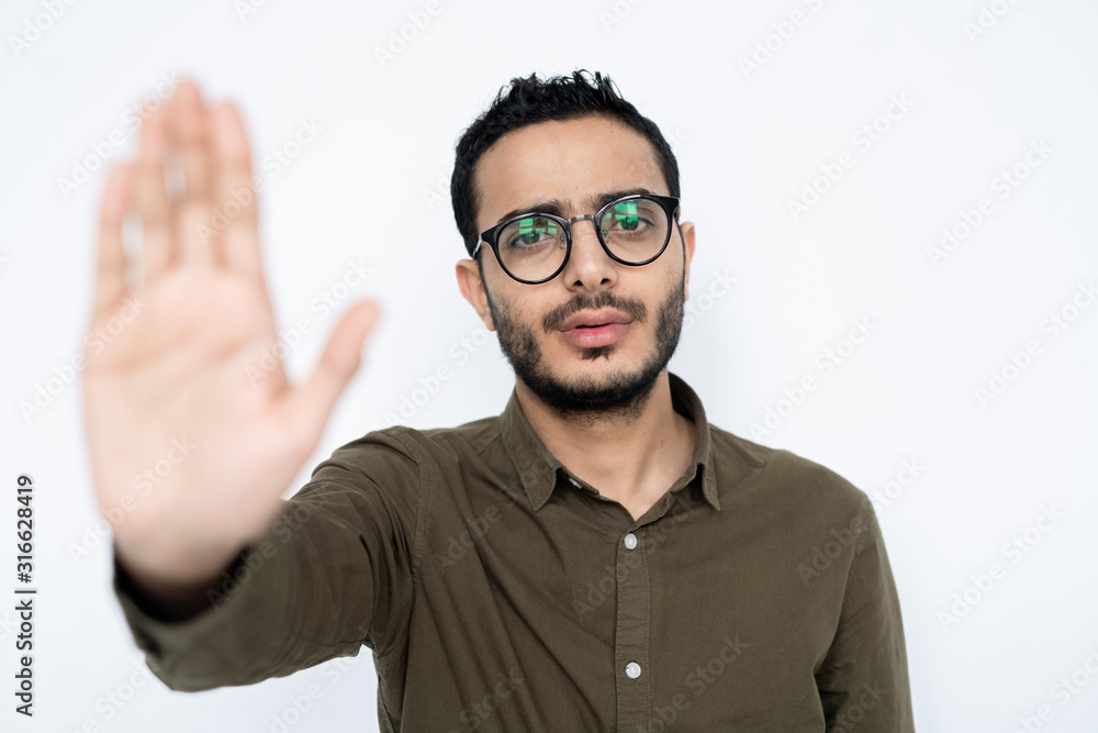 Young man in shirt and eyeglasses showing stop sign to make warning Young man in shirt and eyeglasses showing stop sign to make warning