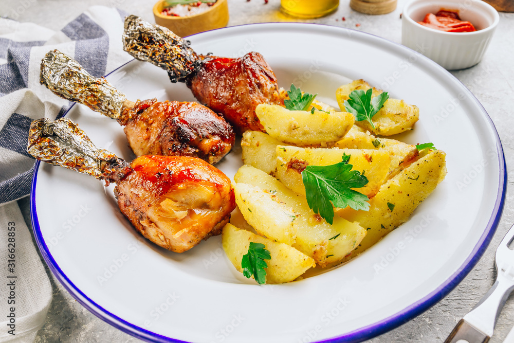 Grilled chicken drumstick bbq with potato slices on a stone gray background. Grilled chicken drumstick bbq with potato slices on a stone gray background.