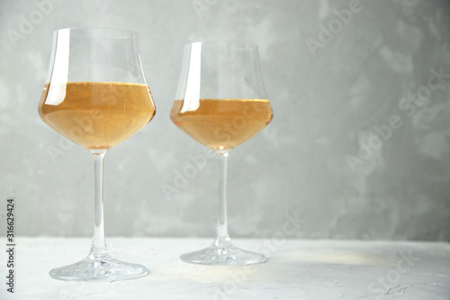 Orange wine in two glass glasses on a gray table and a gray background. Copy space.