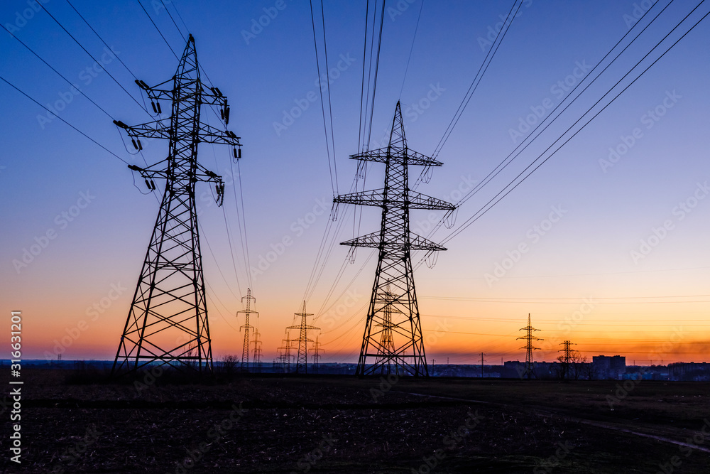 High voltage power line in a field at sunset