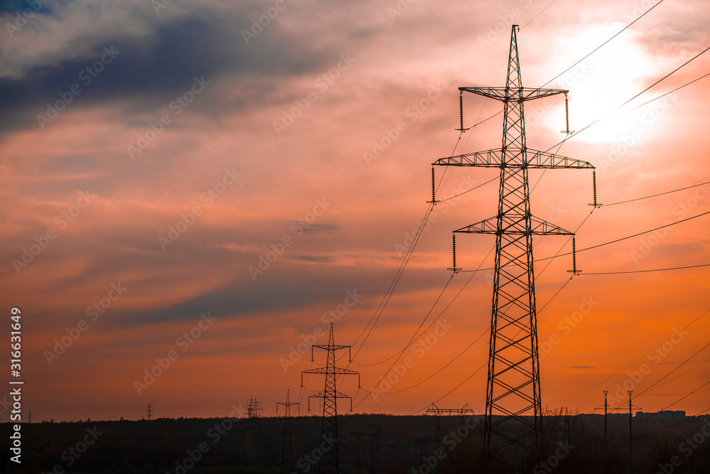 Group silhouette of transmission towers (power tower, electricity pylon, steel lattice tower) at twilight in US. Texture high voltage pillar, overhead power line, industrial background. Copy space