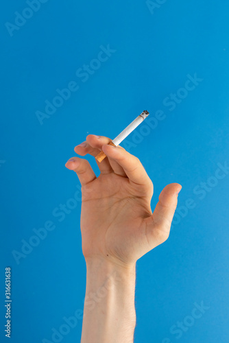 Fototapeta Naklejka Na Ścianę i Meble -  global reason of human death - person hand holding a burning cigarette and smoking isolated on color background