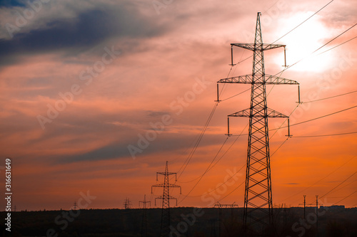Group silhouette of transmission towers (power tower, electricity pylon, steel lattice tower) at twilight in US. Texture high voltage pillar, overhead power line, industrial background. Copy space