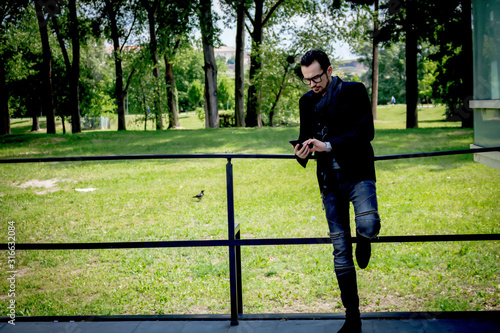 Mid adult man text messaging on mobile phone in the park.