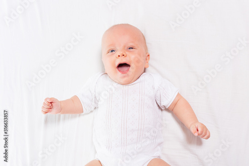 Laughing happy little infant baby boy with open mouth and shining eyes view from above