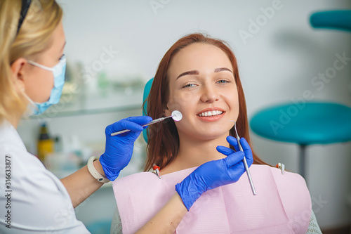 Young beautiful woman with beautiful white teeth sitting on a dental chair. Portrait of a woman with toothy smile sitting during examination at the dental office