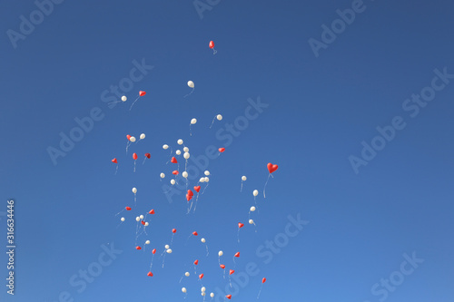 White and red heart balloons in the blue cloudless sky © Root-Couture