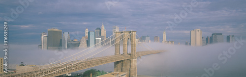Photography New York City, New York shows Brooklyn Bridge with fog under neath it