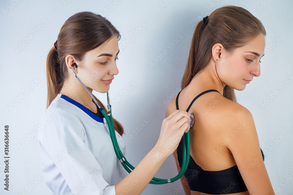 Doctor checking breathing with stethoscop of a female patient. Doctor sitting near the patient and listening to the noise in his organism using a stethoscope. Close-up. Doctor checking breathing with stethoscop of a female patient. Doctor sitting near the patient and listening to the noise in his organism using a stethoscope. Close-up.
