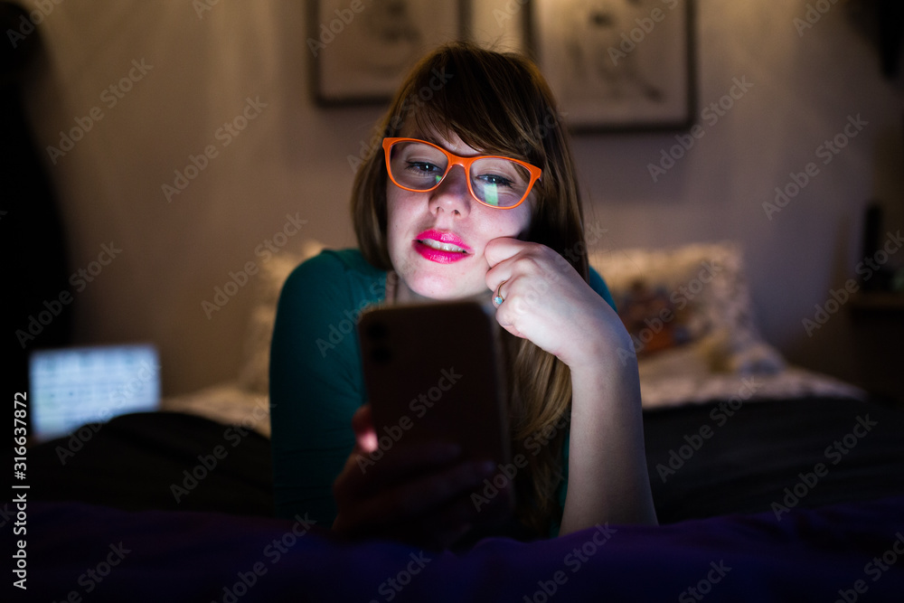 Obraz premium Hipster girl with glasses looking at her mobile phone