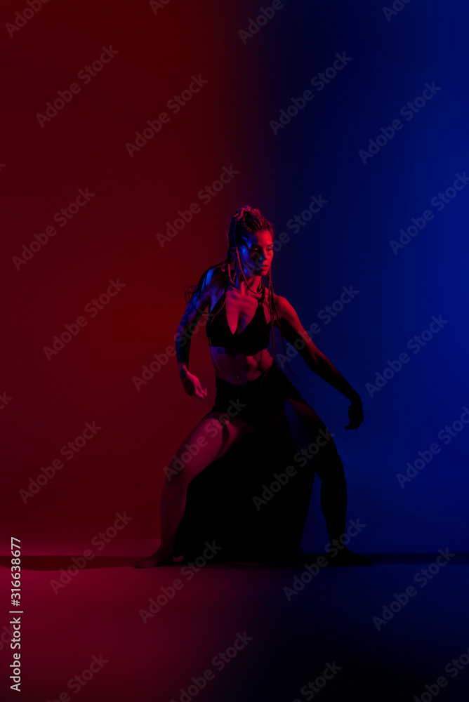 Black dressed and braided hair woman dancing on a blue and red background. Black dressed and braided hair woman dancing on a blue and red background.