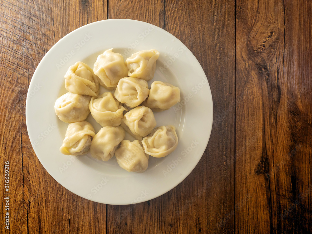 Portion of traditional Russian dumplings on a white plate and wooden table, Top view. Portion of traditional Russian dumplings on a white plate and wooden table, Top view.