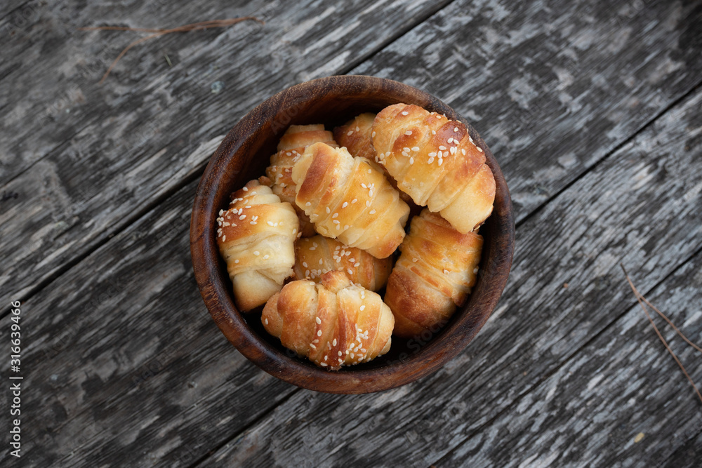 Croissants sprinkled with sesame seeds in a wooden basket. Close-up Croissants sprinkled with sesame seeds in a wooden basket. Close-up