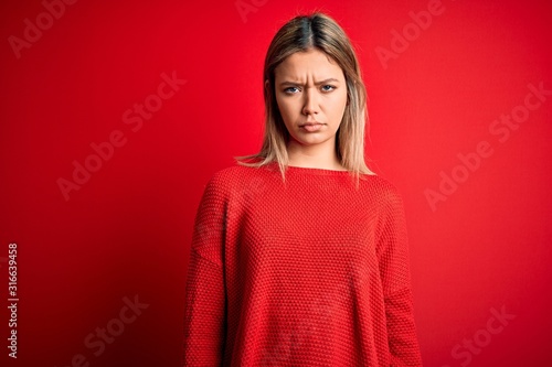 Young beautiful blonde woman wearing casual sweater over red isolated background depressed and worry for distress, crying angry and afraid. Sad expression.