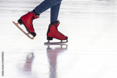 feet in red skates on an ice rink. Hobbies and sports. Vacations and winter activities.