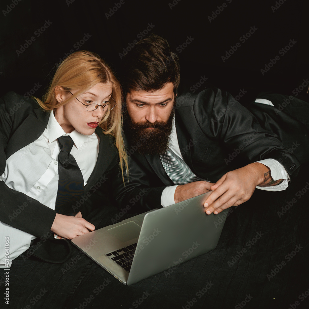 Two business partners working with laptop together. Professional man and woman economist searche information on portable computer. Business person at workplace. Two business partners working with laptop together. Professional man and woman economist searche information on portable computer. Business person at workplace.