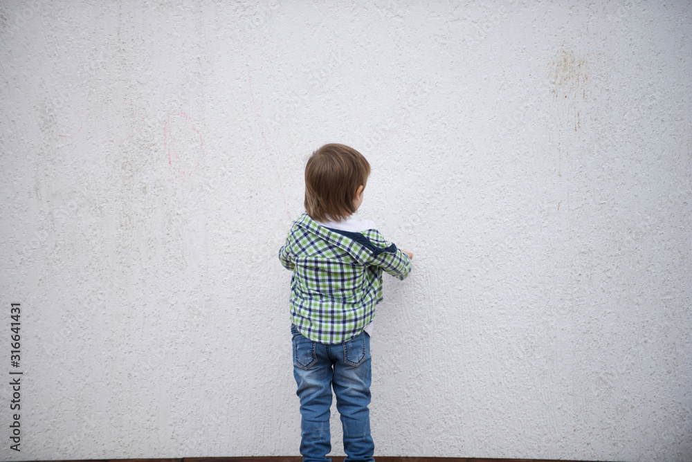 Boy stand facing a white wall. Blurred image Boy stand facing a white wall. Blurred image