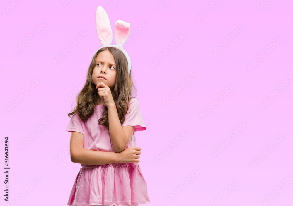 Brunette hispanic girl wearing easter rabbit ears serious face thinking about question, very confused idea