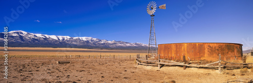 This is an old wooden windmill in an open field in the old west.