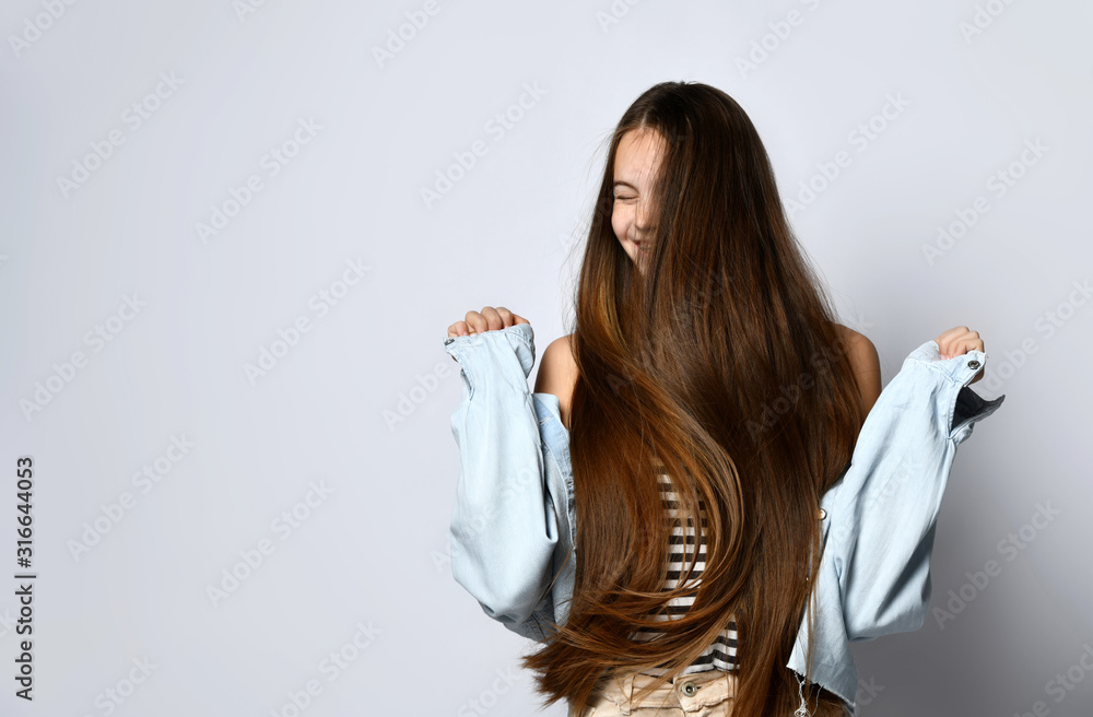 Teenager with long hair, in striped t-shirt and denim jacket. She is laughing, posing isolated on white studio background.Close up Teenager with long hair, in striped t-shirt and denim jacket. She is laughing, posing isolated on white studio background.Close up
