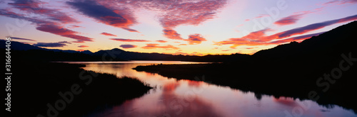 This is Lake Casitas at sunrise. There is a pinkish glow from the sun reflected in the lake.