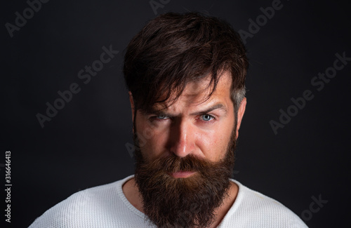 Head and shoulders portrait of a bearded middle-aged man looking at the camera over a black studio background with copy space.