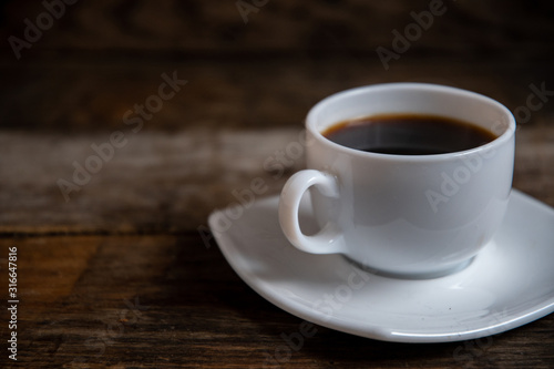 White cup of espresso coffee on a wooden background.