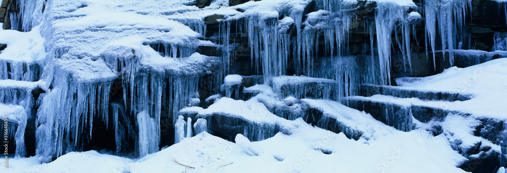 These are Icicles in the Sierra Mountains in winter. The icicles overhang the ledges they are formed upon. - obrazy, fototapety, plakaty 