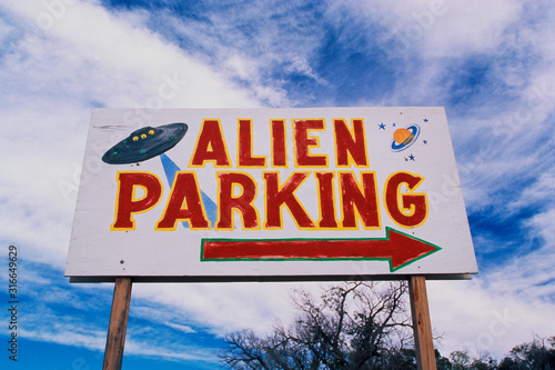This is a road sign indicating where Alien Parking is. This is the original UFO crash site in Roswell. There are small UFOs on the sign with a large arrow pointing to the right. photo