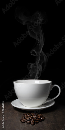 White porcelain cup and saucer on black background with steam