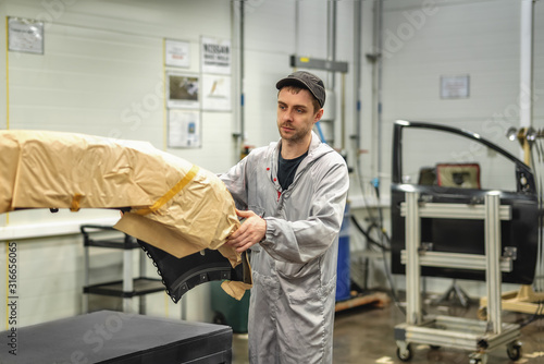 An employee of the paint shop of the automobile plant prepares bumpers for painting