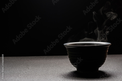 Soup hot in black bowl on wooden table,food steam and copy space ,selective focus.Fresh foods concept