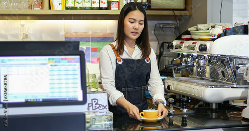 Asian women Barista smiling and using coffee machine in coffee shop counter - Working woman small business owner food and drink cafe concept