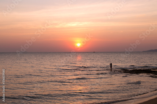 Fisherman on sea pink sunset background. Beautiful color clouds.