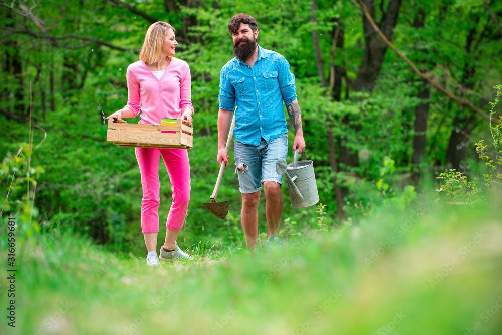 Couple of farmers walking in agricultural field. Gardening in spring - happy couple harvesting and having lots of fun. A pair of farms working in the garden.