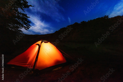 Fantastic starry night with galaxy Milky Way with a tourist and a tent on the mountain range in the Ukrainian Carpathians 