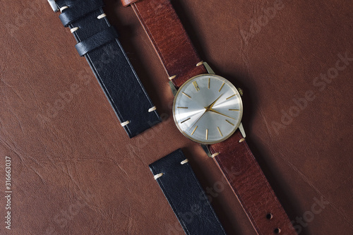 Vintage wristwatch on a brown leather background. Classic watch straps, Genuine handcraft italian calfskin leather with white top stitching.