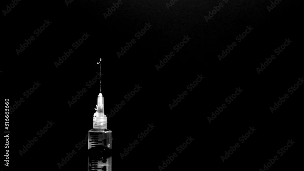 Needle squirts liquid in slow motion in front of black background. Needle squirts liquid in slow motion in front of black background.