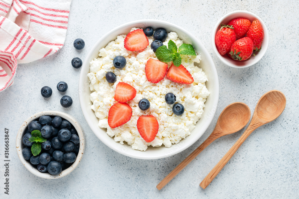 Cottage cheese, curd cheese with fresh summer berries in a bowl, table top view. Healthy dairy