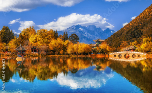 Panorama Landscape view of the Black Dragon Pool at Jade Spring Park with marble bridge over the Jade dragon mountain under blue sky, Lijiang, Yunnan province, China. China culture and travel concept