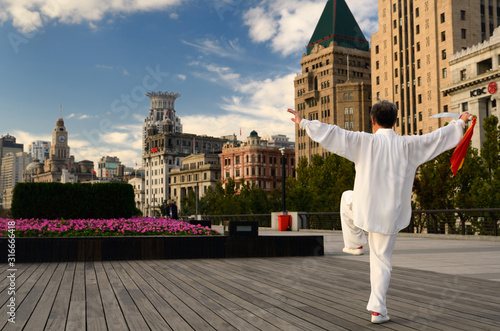 Man in white with Tai Chi sword exercising on the Bund at dawn in Shanghai China photo