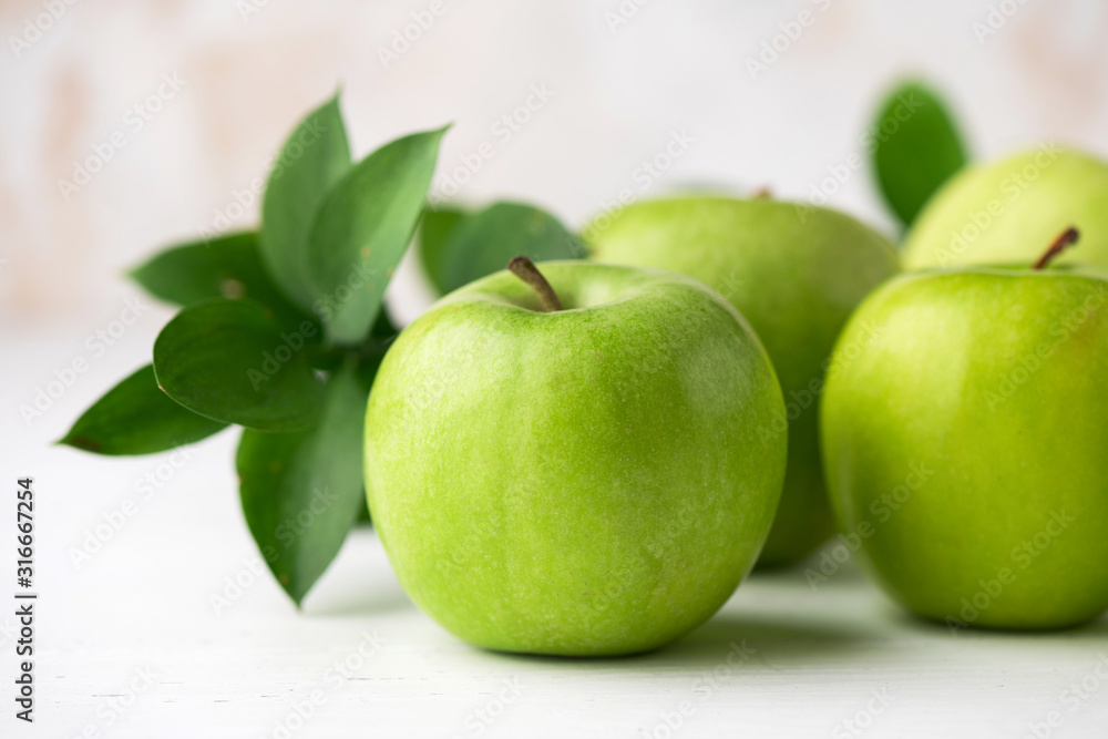 Green apples with green leaf on white table closeup view. Healthy crispy fresh fruits Green apples with green leaf on white table closeup view. Healthy crispy fresh fruits