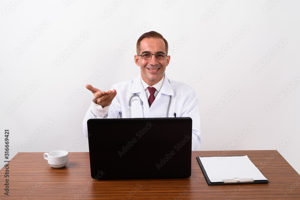 Mature Persian man doctor working behind desk Mature Persian man doctor working behind desk