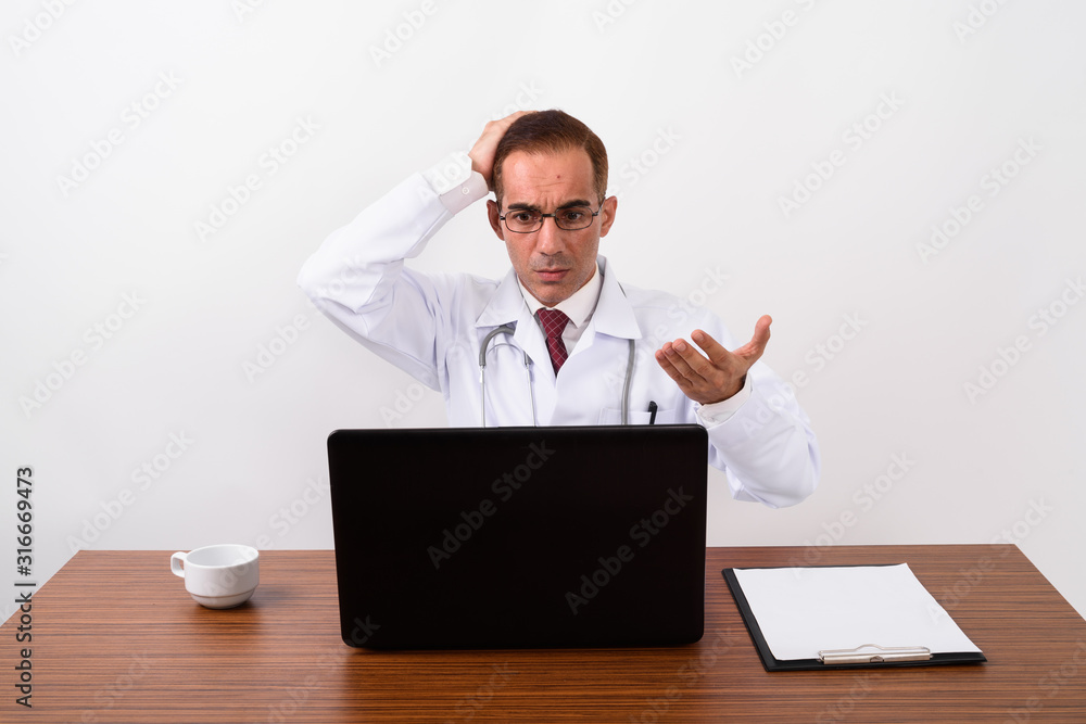 Mature Persian man doctor working behind desk Mature Persian man doctor working behind desk