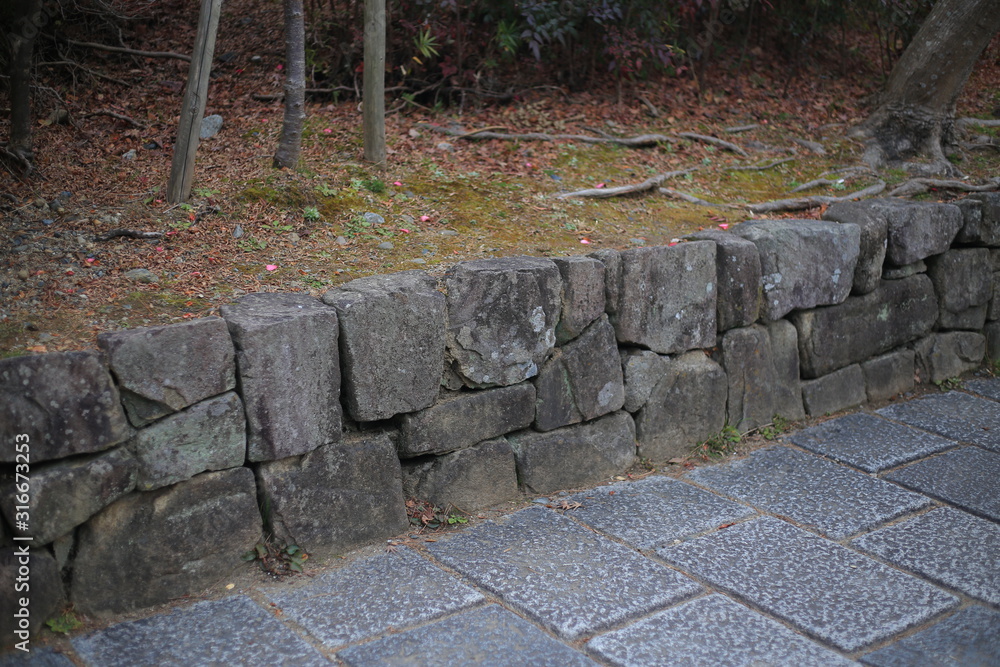 cut stone retaining wall separate green area and rough granite stone